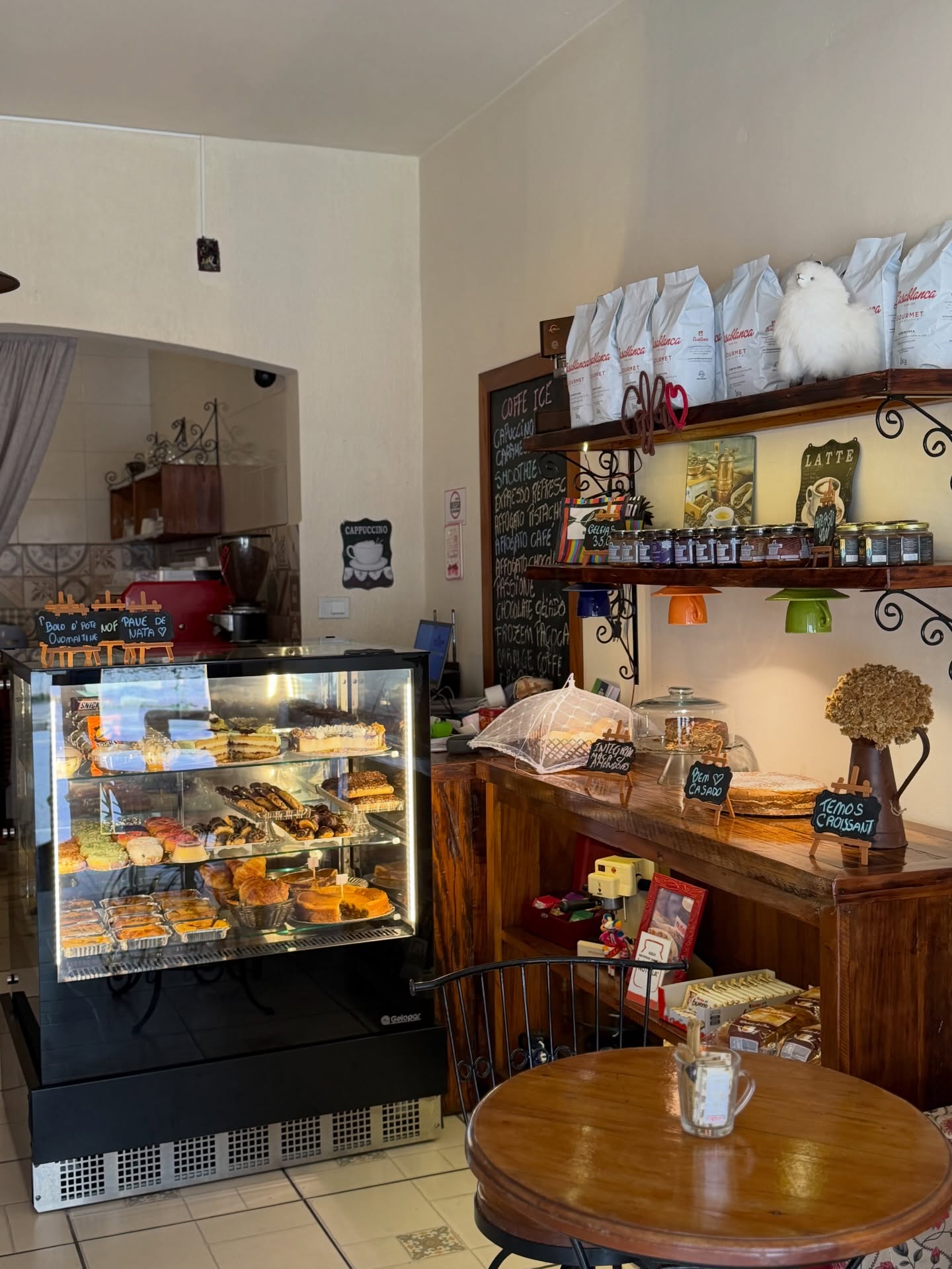 Interior do café com a vitrine iluminada e a lousa de bebidas